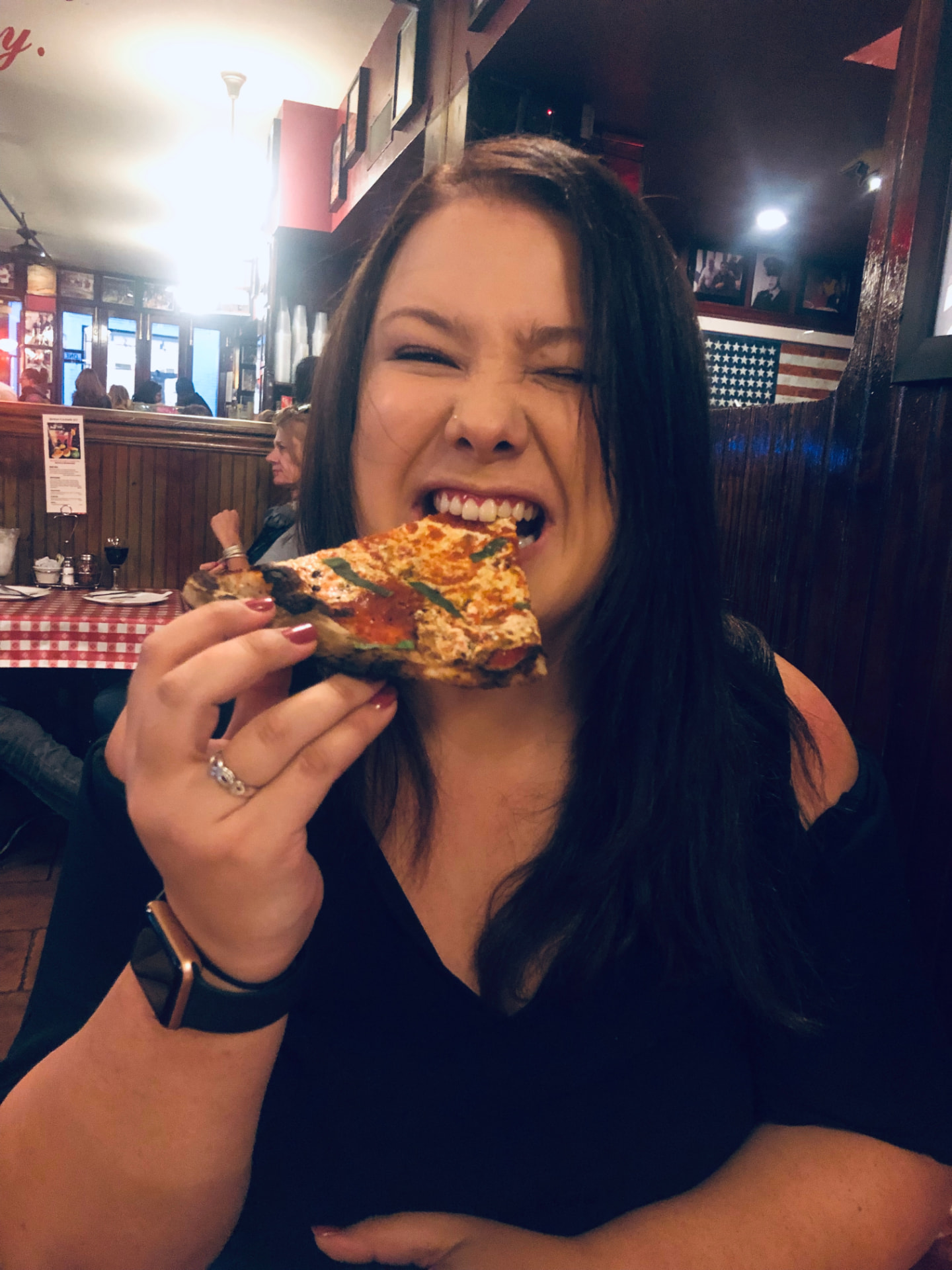 Caitlin biting into a slice of pizza